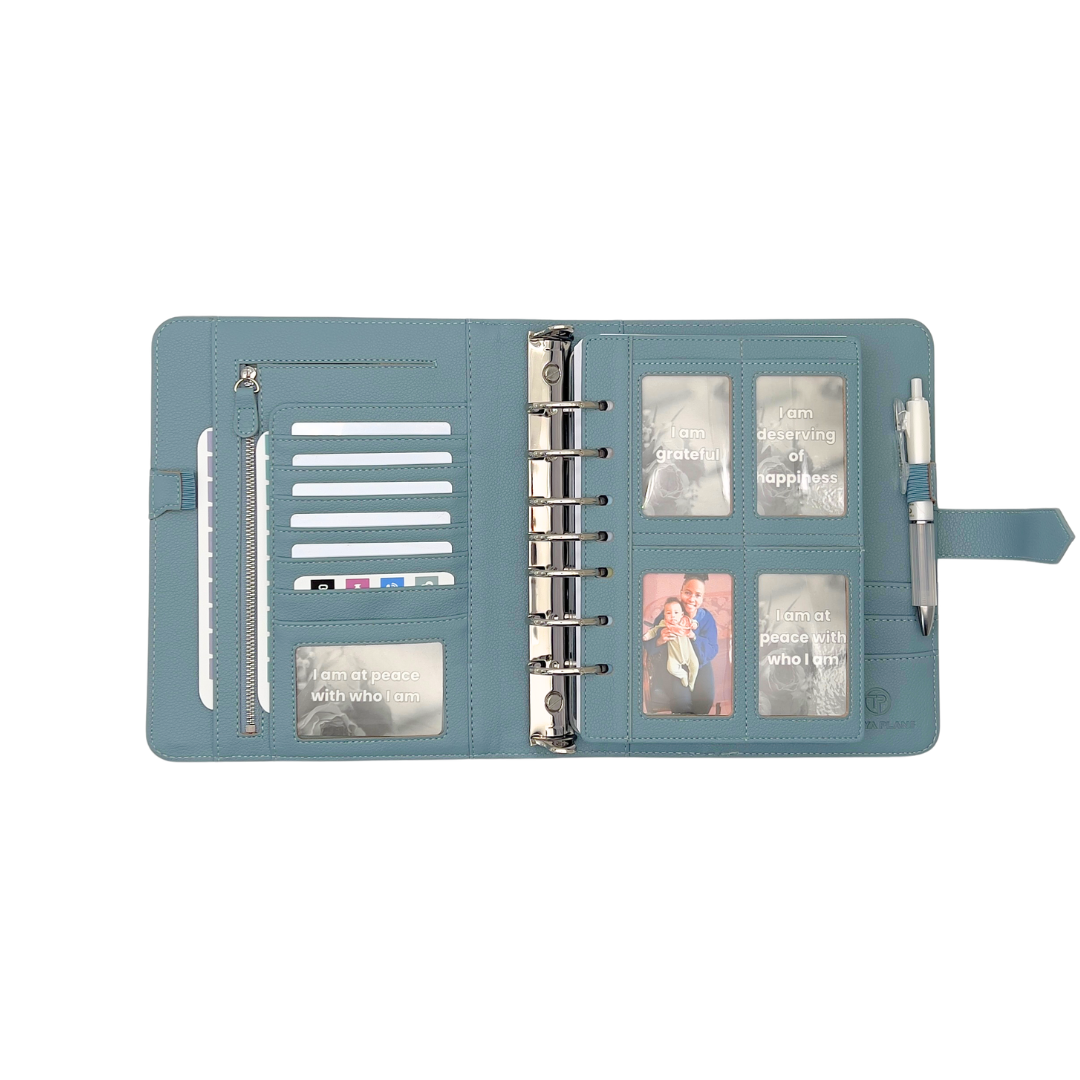 Blue planner with photo sleeves and a pen on a white background