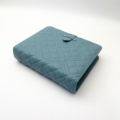 Blue genia quilted binder laying on white surface