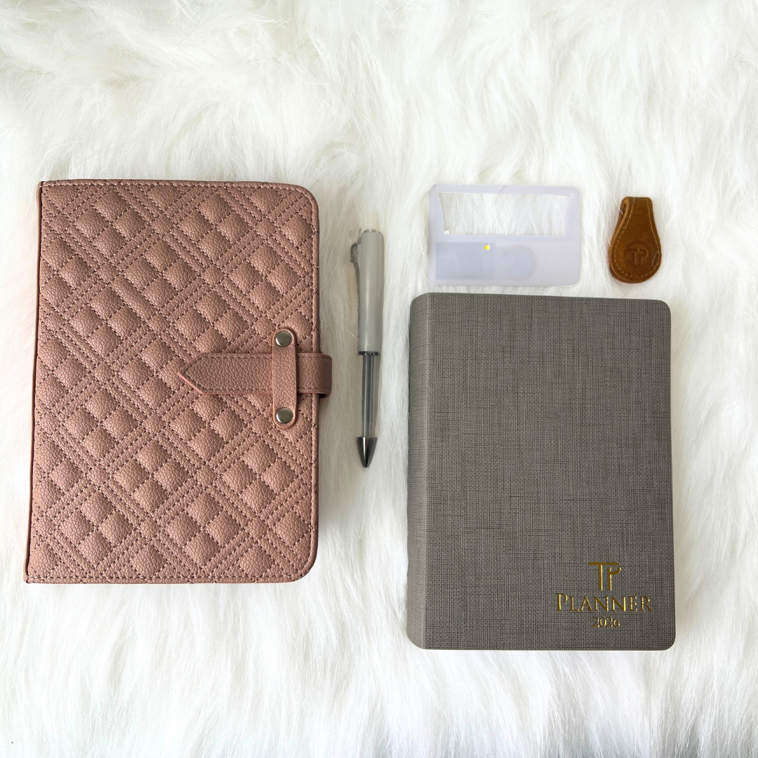 Two planners, a pen, and a small pouch on a white fur surface