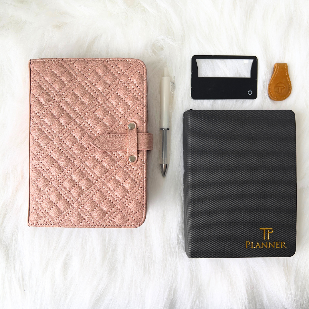 Pink quilted planner, black planner with 'TP Planner' branding, pen, and small planner items on a white surface.